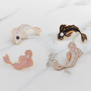 Detailed overhead view of four colorful enamel koi fish pins on white marble surface