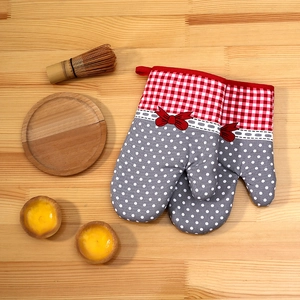 Detailed view of red plaid and grey polka dot oven mitts on a rustic wooden table