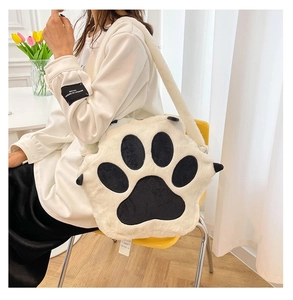Close-up of white plush cat paw crossbody bag with black paw pads on a model