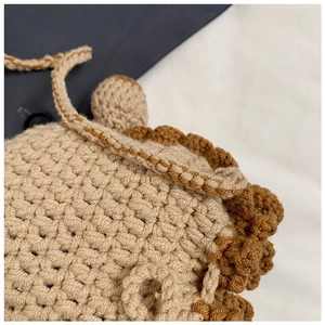 Close-up of beige crochet handbag showing intricate yarn textures and brown knit edges