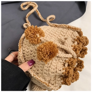 Close-up of handmade crochet bear bag with beige yarn texture and fuzzy pom poms