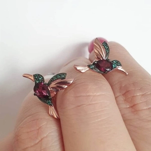 Detail of hummingbird earring in rose gold finish with red and green cubic zirconia