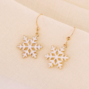 Detail of snowflake earrings with white enamel and gold plating for winter festive style