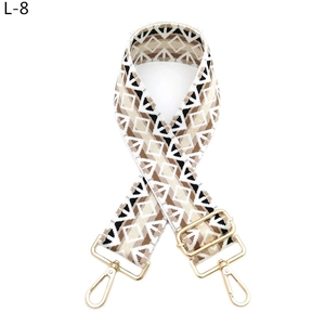 Close-up of geometric diamond pattern woven bag strap with golden metal lobster clasps