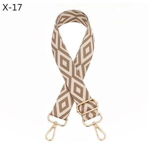 Detail of adjustable woven bag strap with beige and brown geometric patterns and gold clips