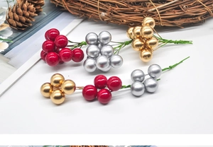 Close-up of red gold and silver Christmas berry picks with pine cones on white table