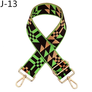 Detail of adjustable woven bag strap with green geometric patterns and gold metal hooks