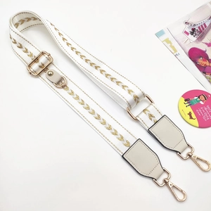 Adjustable beige bag strap with golden chevron embroidery and metallic hardware details