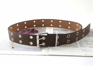 Close-up of brown double-eyelet leather belt with silver double-pin metal buckle