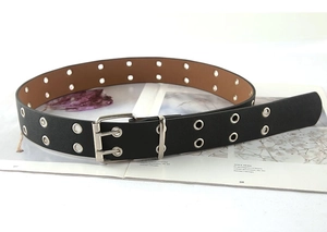 Detail of black punk leather belt with double silver eyelets and a twin-prong metal buckle