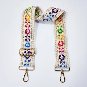 Close-up of bohemian guitar style strap with colorful embroidery and gold metal hooks
