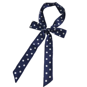 Navy blue polka dot long skinny scarf tied in a bow on a clean white background