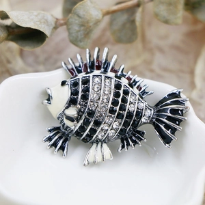Macro detail of a fish brooch with black and white rhinestones on a ceramic dish