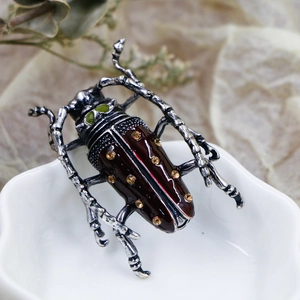 Macro shot of retro silver beetle brooch with brown enamel and yellow rhinestones