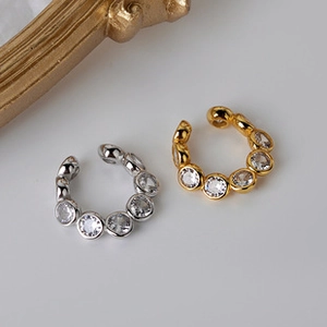 Detailed view of two minimalist ear cuffs with seven inlaid zircons in gold and silver