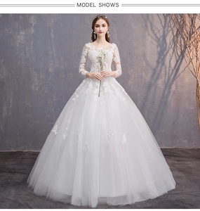 Dettaglio delle maniche lunghe in pizzo e dei ricami elaborati sull'abito da sposa