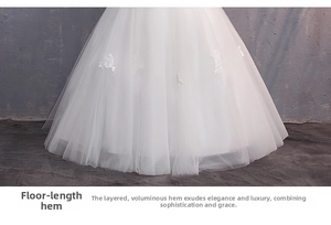 Dettaglio dell'abito da sposa bianco con ricami floreali in pizzo e orlo in tulle multistrato lungo