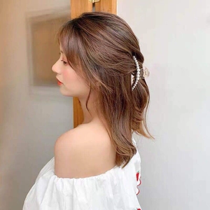 Detail of elegant pearl hair claw clip worn on head for half-up hair styling