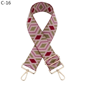 Detail of adjustable bag strap with pink, red, and olive green diamond pattern and gold hooks