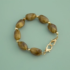 Detailed macro shot of irregular amber acrylic beads with gold spacers and lobster clasp