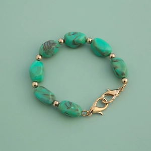 Detailed macro view of green marbled acrylic stones and golden spacer beads on chain