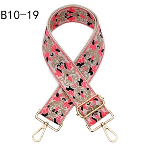 Detail of ethnic jacquard purse strap with pink floral embroidery and gold metal clasps