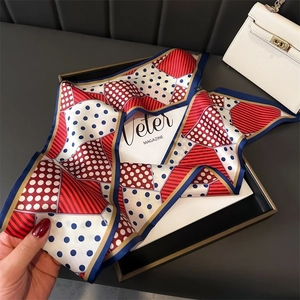 Detailed close-up of a tricolor polka dot silk scarf draped over a black jewelry box