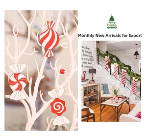 Detail of red and white striped candy and sock wooden ornaments hanging on a white branch