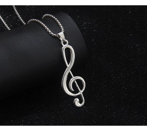 Macro shot of silver stainless steel treble clef musical note pendant on black background