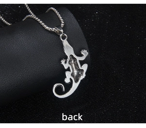 Macro view of the textured back of a retro silver lizard pendant with bead chain