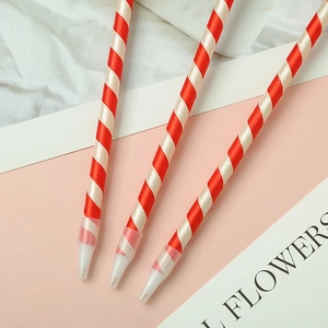 Creative Christmas bell pens with red and white striped ribbon wrap on soft pink background