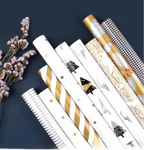 Detail view of assorted wrapping paper rolls with gold metallic patterns and dry flowers