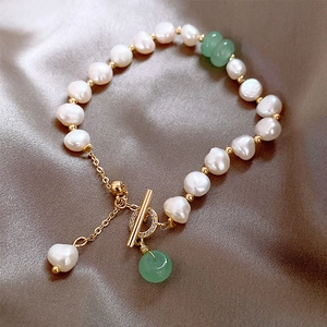 Close-up of baroque pearl bracelet with gold OT clasp on champagne silk background