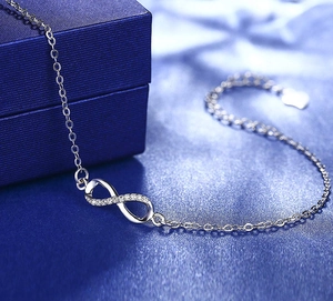 Close-up of infinity symbol pendant with pavé diamonds on blue silk background