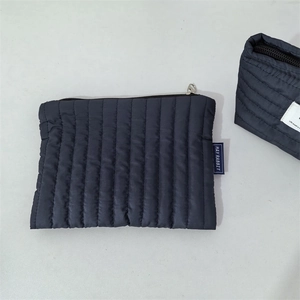 Detail der dunkelblauen gesteppten Kosmetiktasche mit Reißverschluss und Label