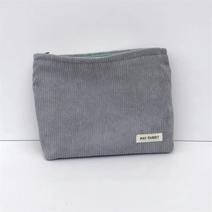 Detail view of grey corduroy makeup bag with mint green zipper and branded label