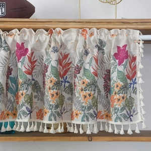 Floral linen cotton coffee curtain with white tassel fringe hanging on a wooden rod