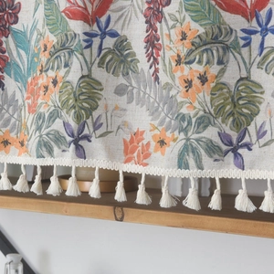 Close-up of tropical floral linen curtain with elegant beige tassel fringe details