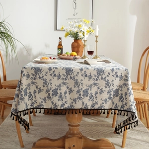 Detailed close-up of the cotton linen tablecloth featuring blue floral patterns and black fringe