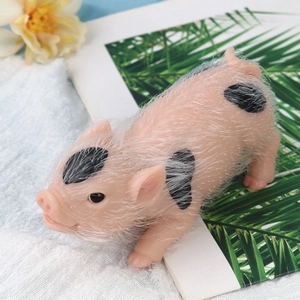 Close-up of pink spotted silicone pig toy with realistic fur texture on white cloth