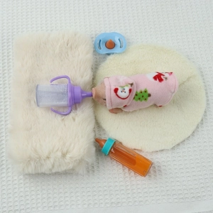 Detail view of mini silicone pig doll with festive pink clothes, bottles and plush accessories