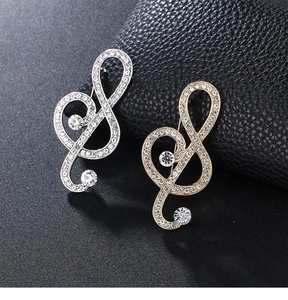 Detailed view of silver and gold treble clef brooches with crystal pavé and large round stones