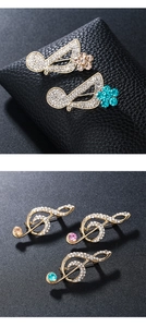 Macro detail of music note brooches with sparkling crystals and colored gems on black leather