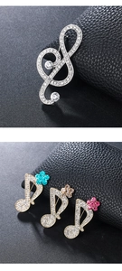 Macro view of musical note brooches with sparkling crystals on black leather background