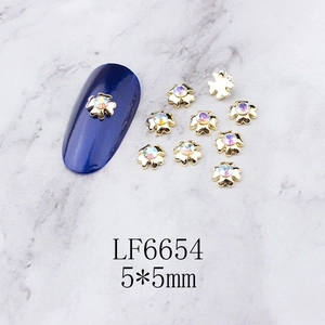 Detail of 5x5mm golden clover nail charms with AB crystals on a blue matte nail plate