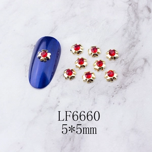 Macro view of 5x5mm gold alloy nail charms with red rhinestones and floral design