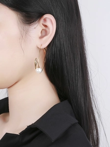 Close-up of gold oversized hoop earring with pearl accent on model for style reference