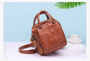Detail of tan textured leather backpack and handbag showing natural grain and side profile