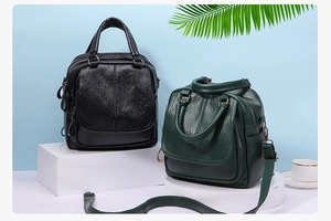Versatile black and dark green faux leather backpack and handbag displayed on a podium