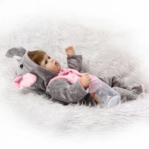 Realistic baby doll with brown hair in pink elephant onesie lying on a white rug